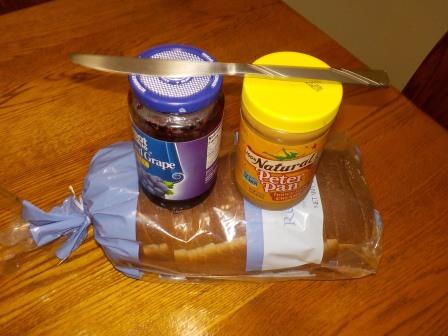 Peanut butter and jelly on bread with a knife.